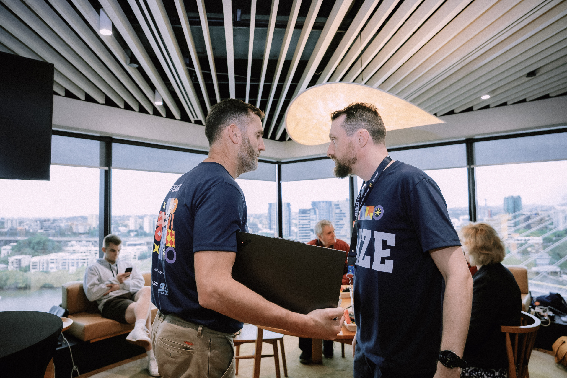 Two Wize team members speaking in the lounge area with city views in the background