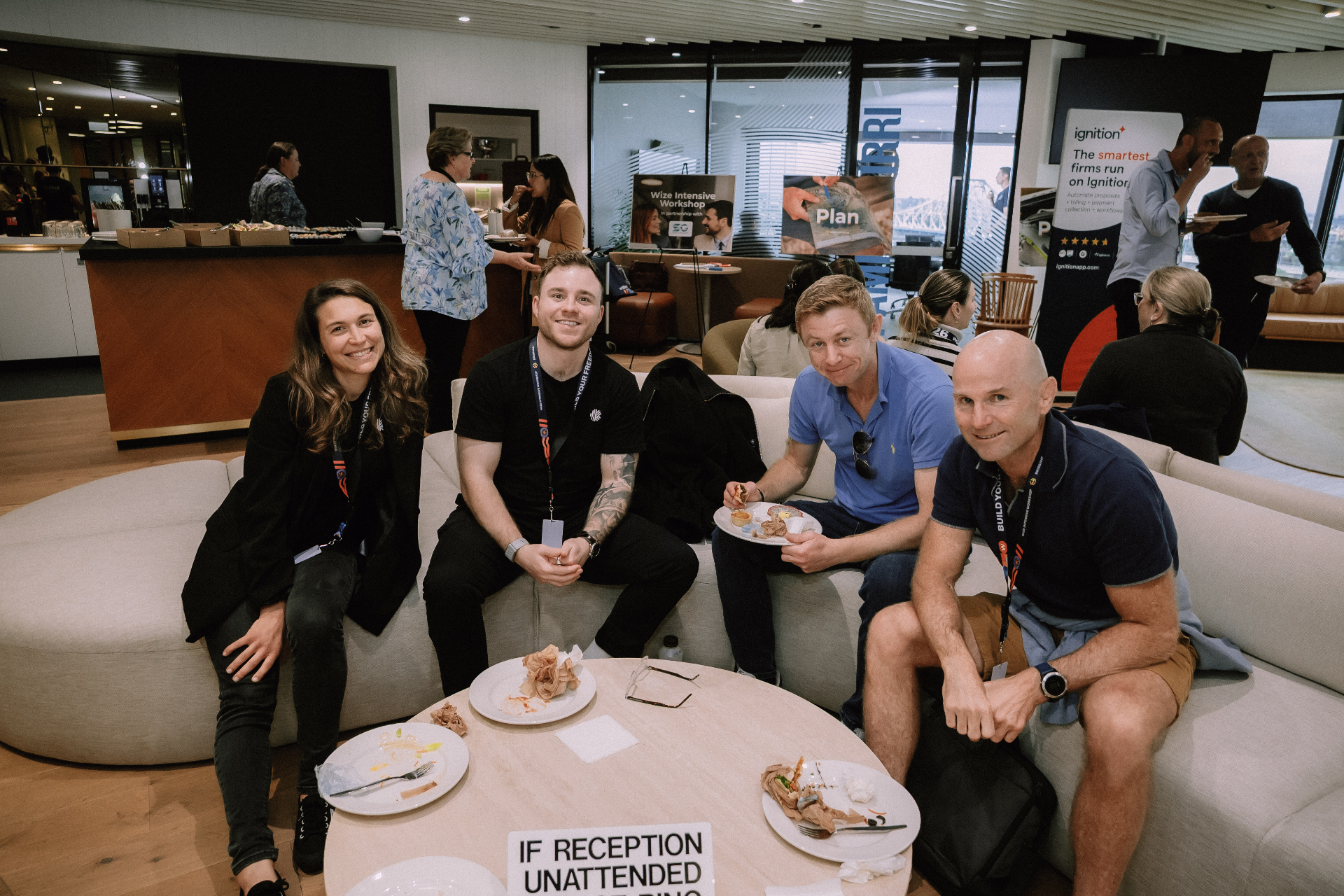 Four attendees relaxing on lounges in the networking area with food and drinks