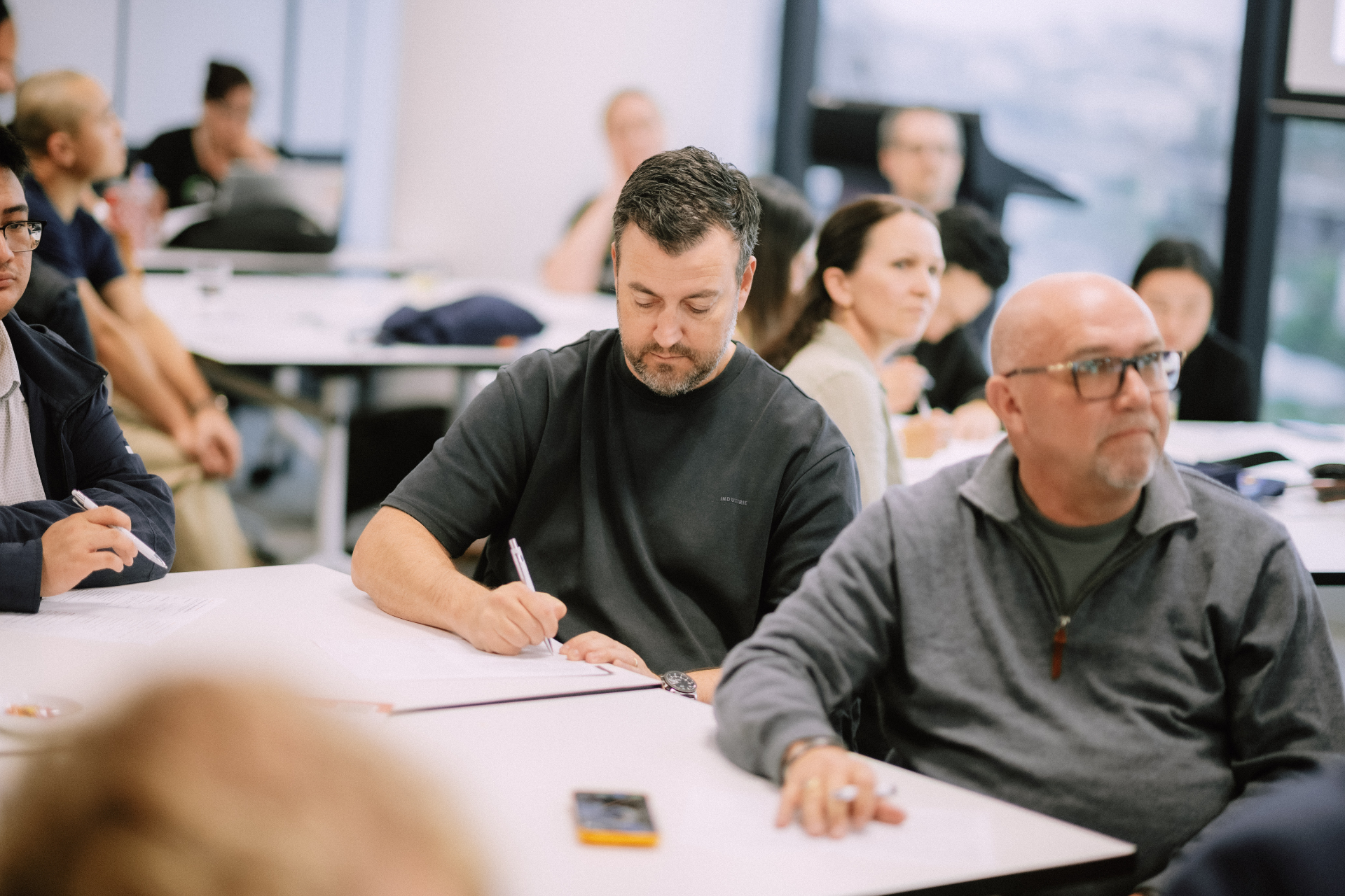 Attendees taking notes at the table during a focused Day 4 workshop session