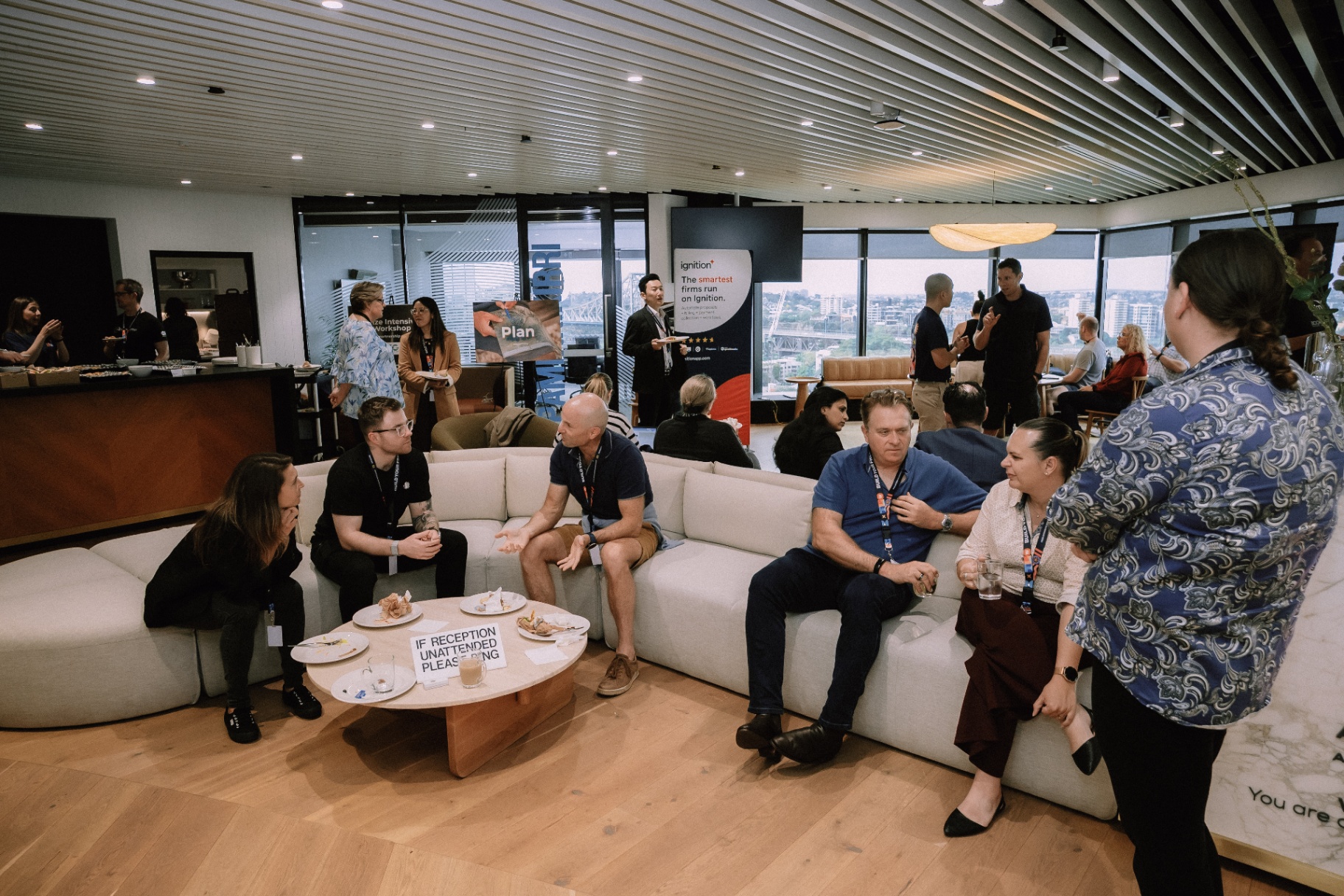Wide lounge view of attendees talking in small groups during the Day 4 event