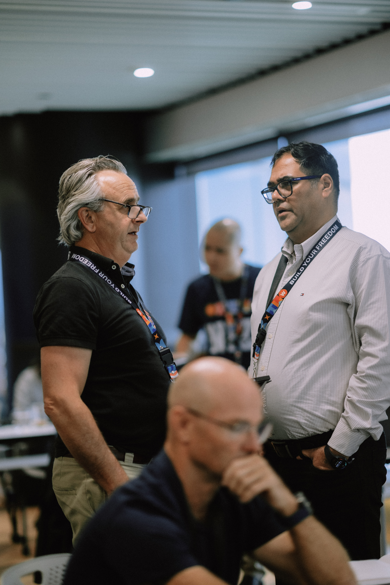 Two attendees chatting while others work in the May 25 Day 1 room