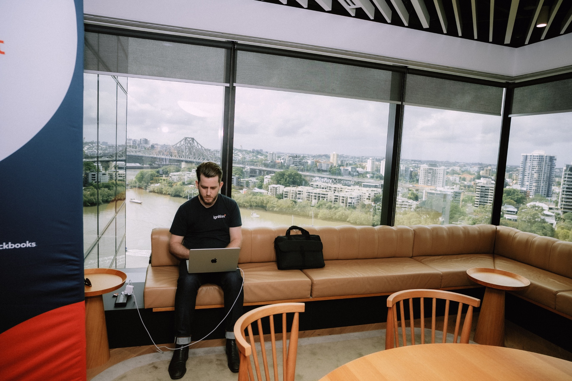 Attendee working on a laptop in the lounge with views over the Brisbane River and Story Bridge