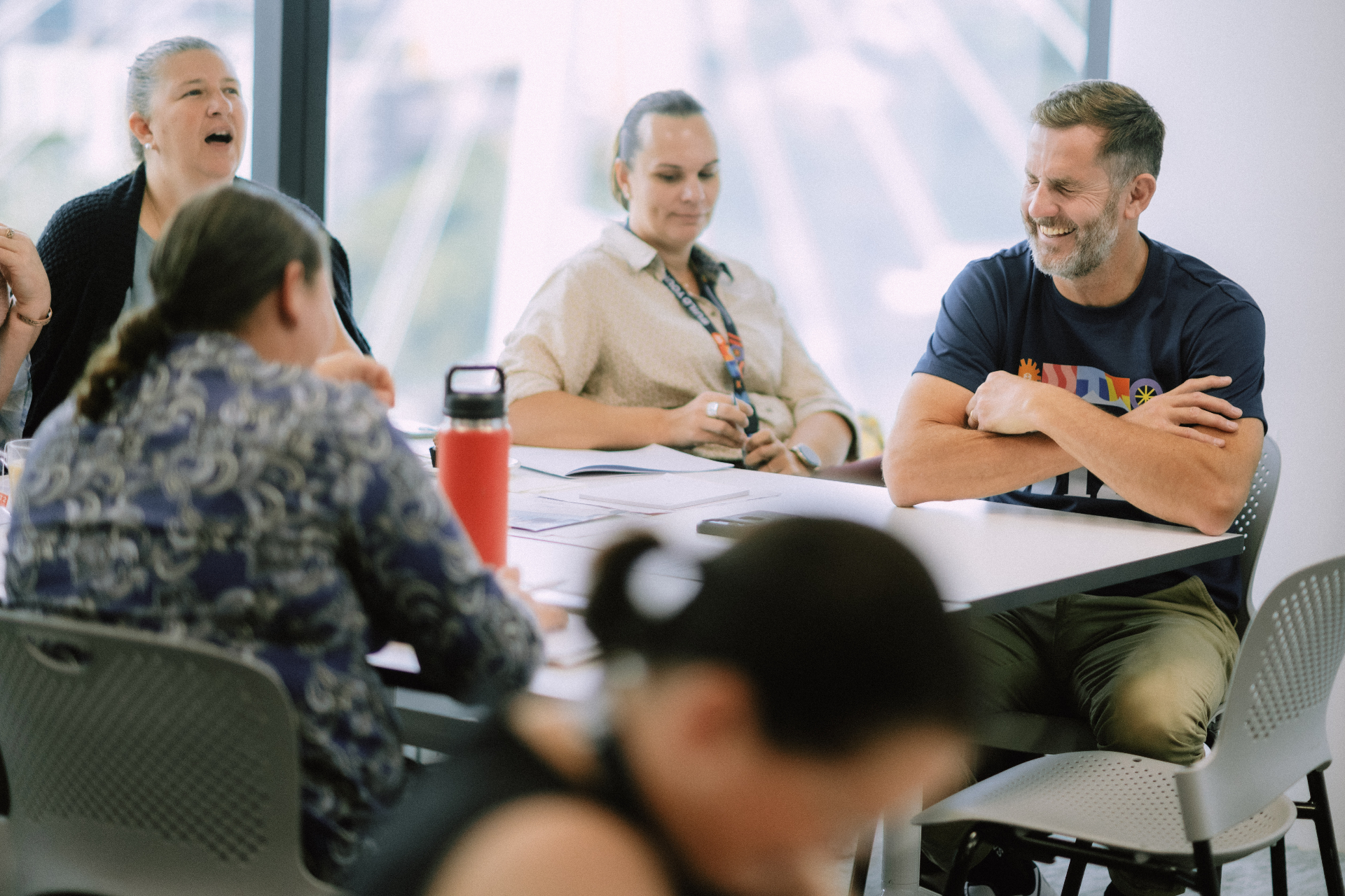 Facilitator laughing with attendees during a relaxed table discussion