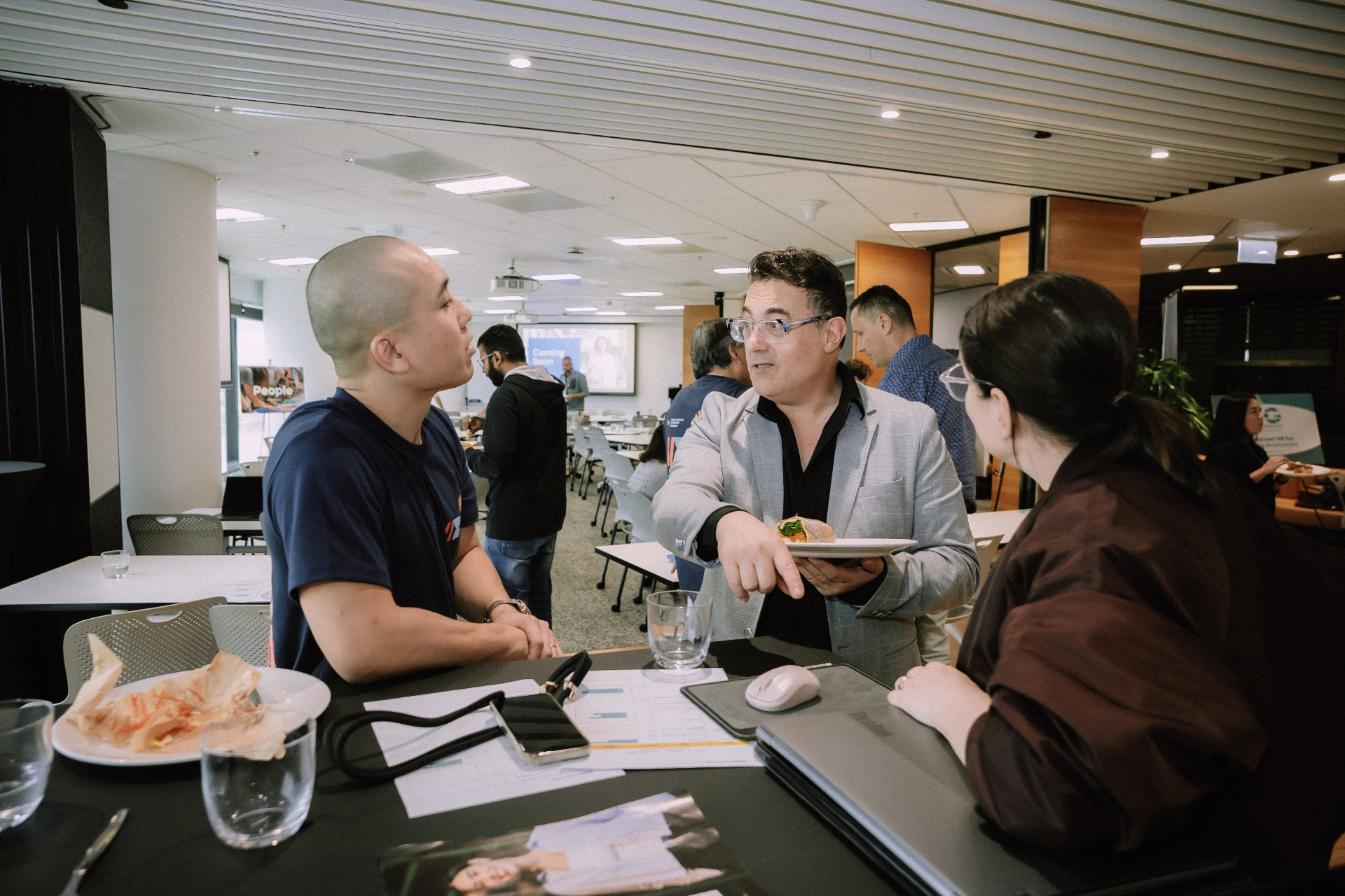 Small group conversation around a high table during a Day 4 networking break