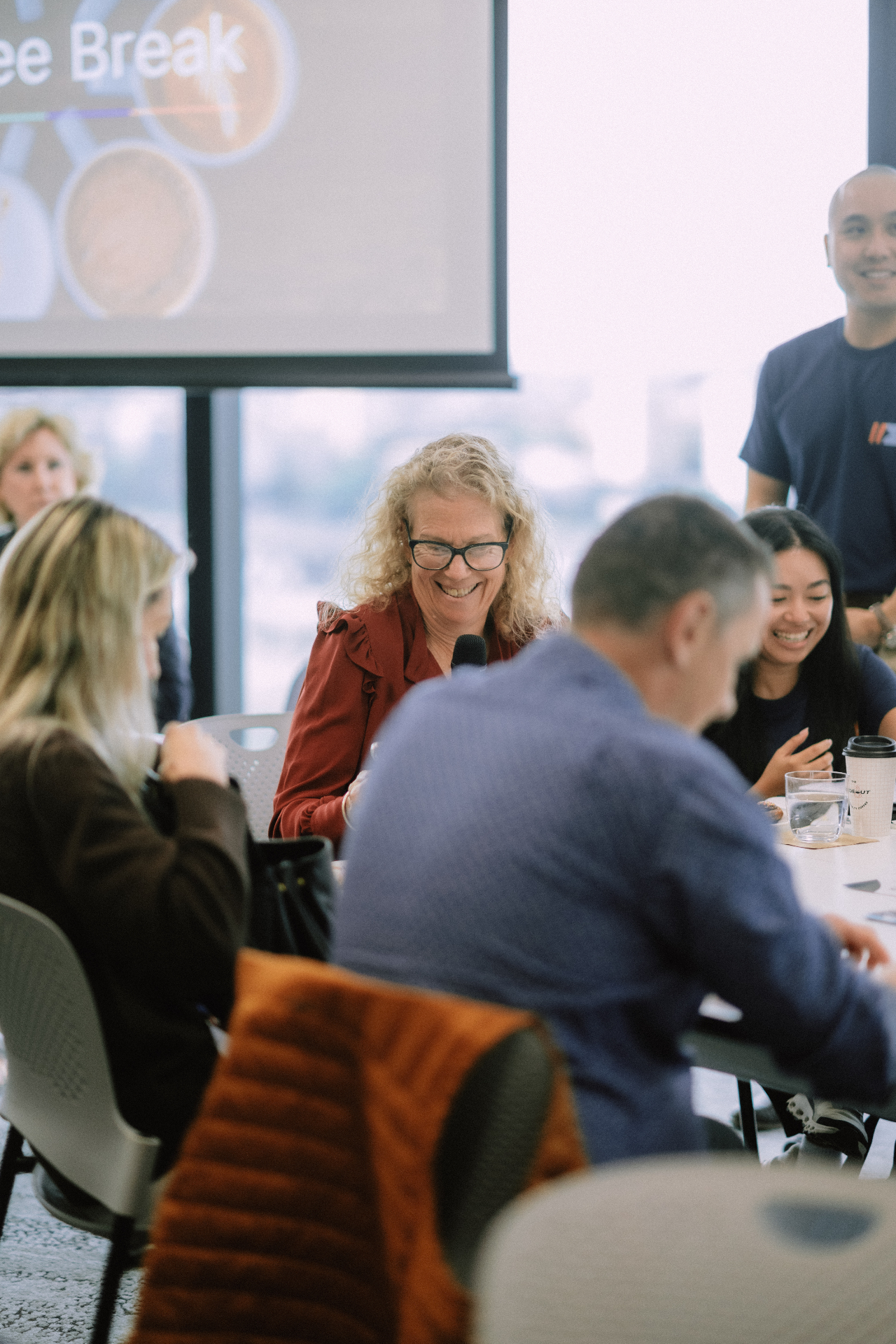 Attendee smiling while speaking into the microphone during the Day 4 coffee break discussion