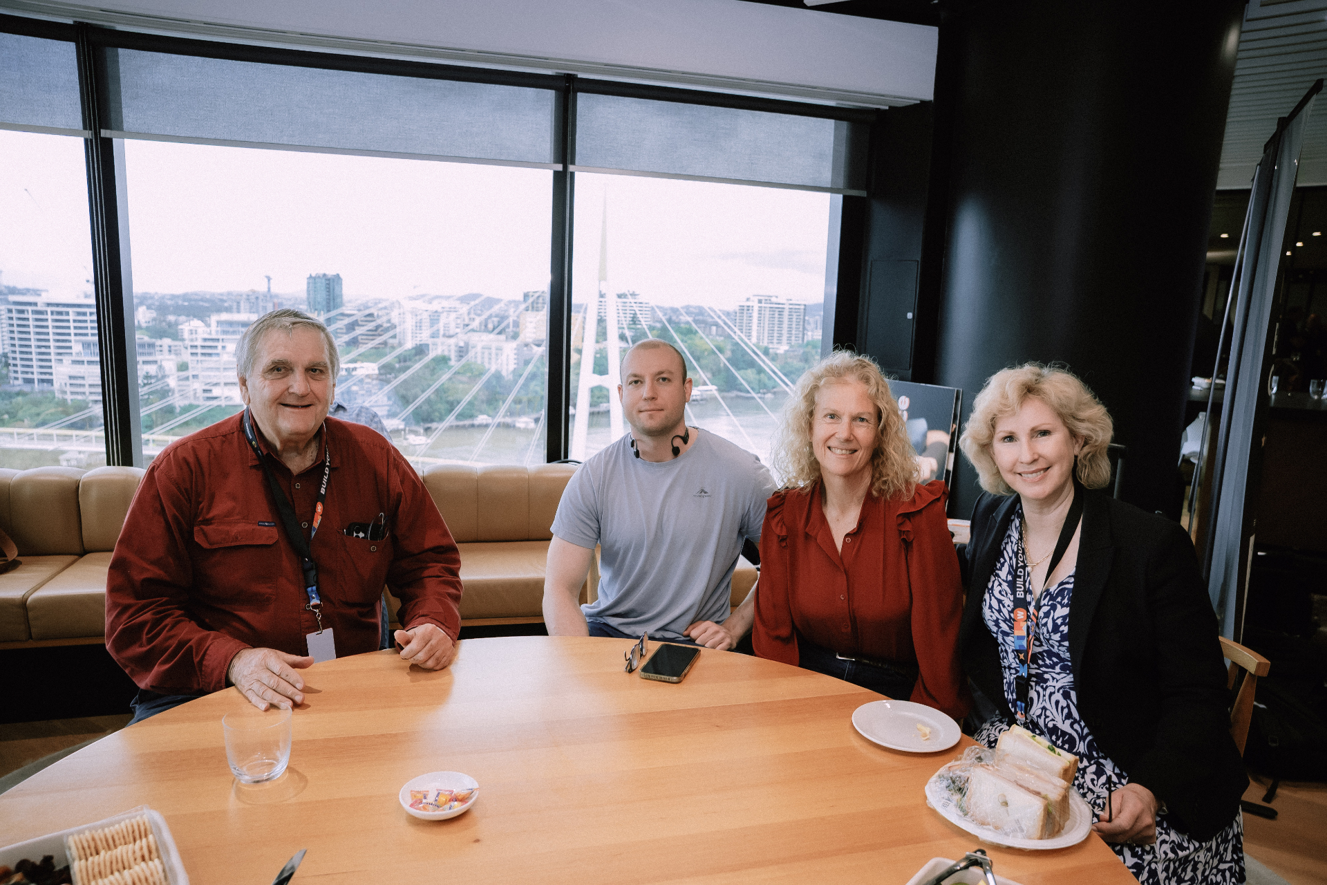 Four attendees seated together at a table with Brisbane river views behind them