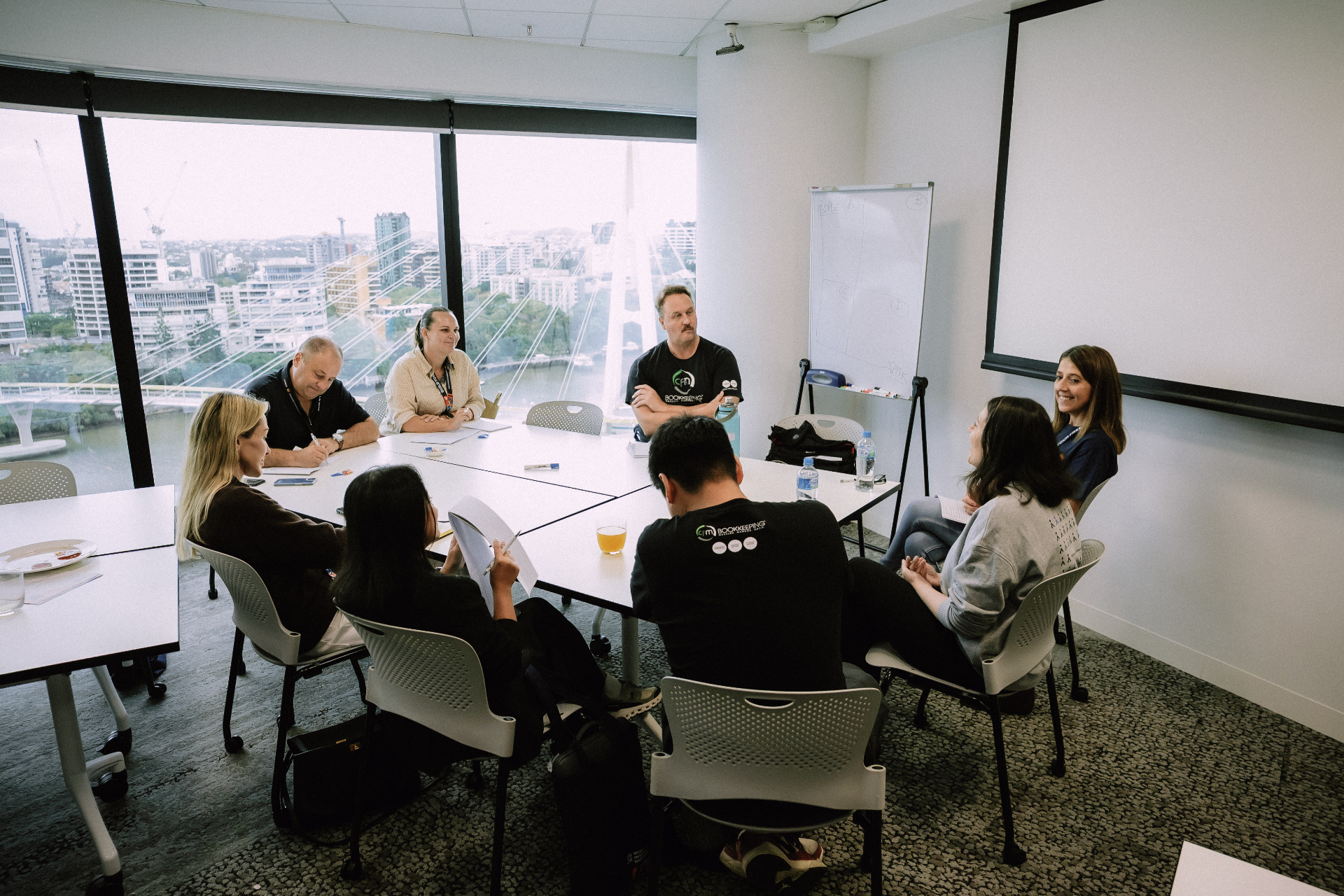 Workshop breakout group seated in discussion with Brisbane river views behind them