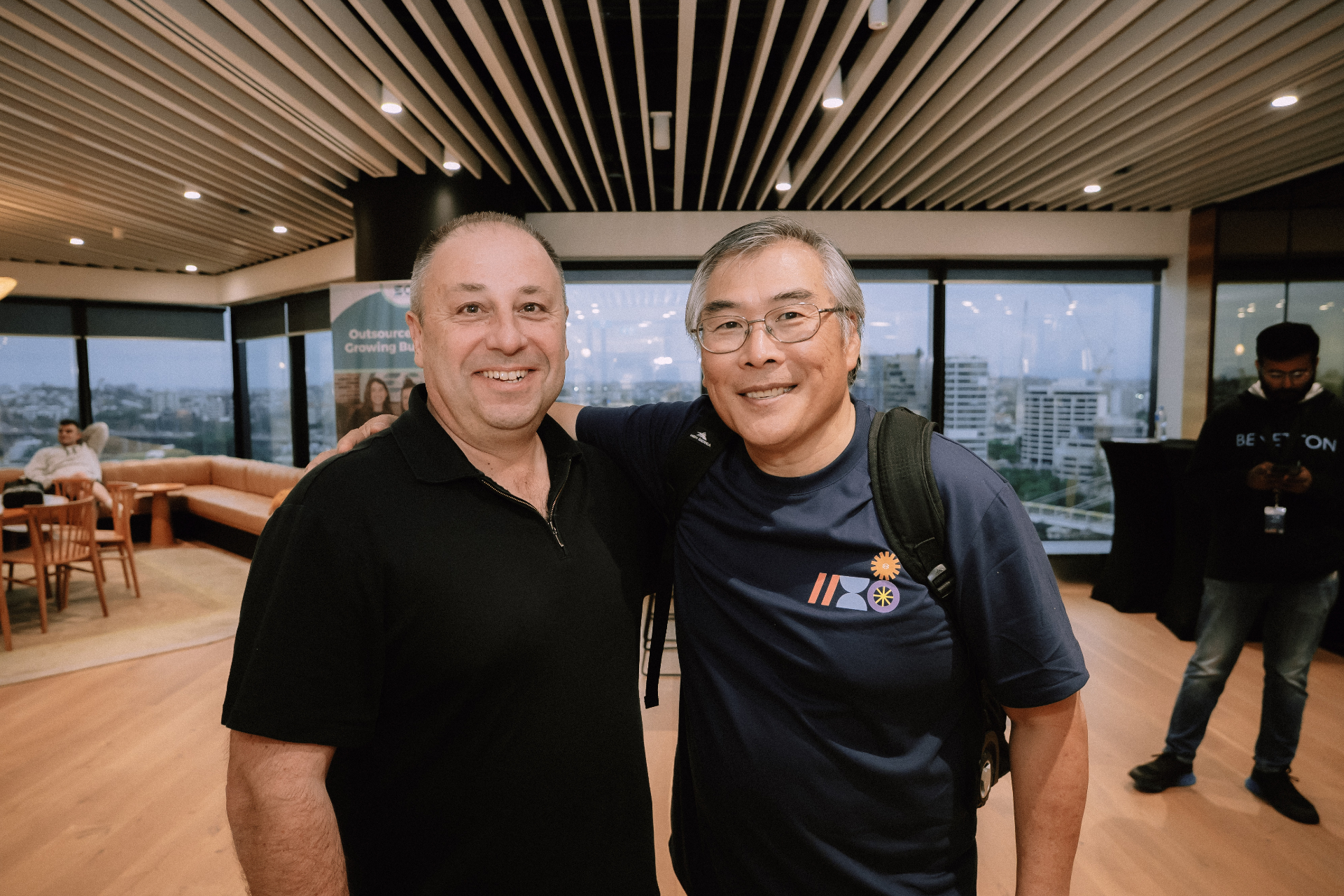 Two attendees smiling together with Brisbane city views in the background
