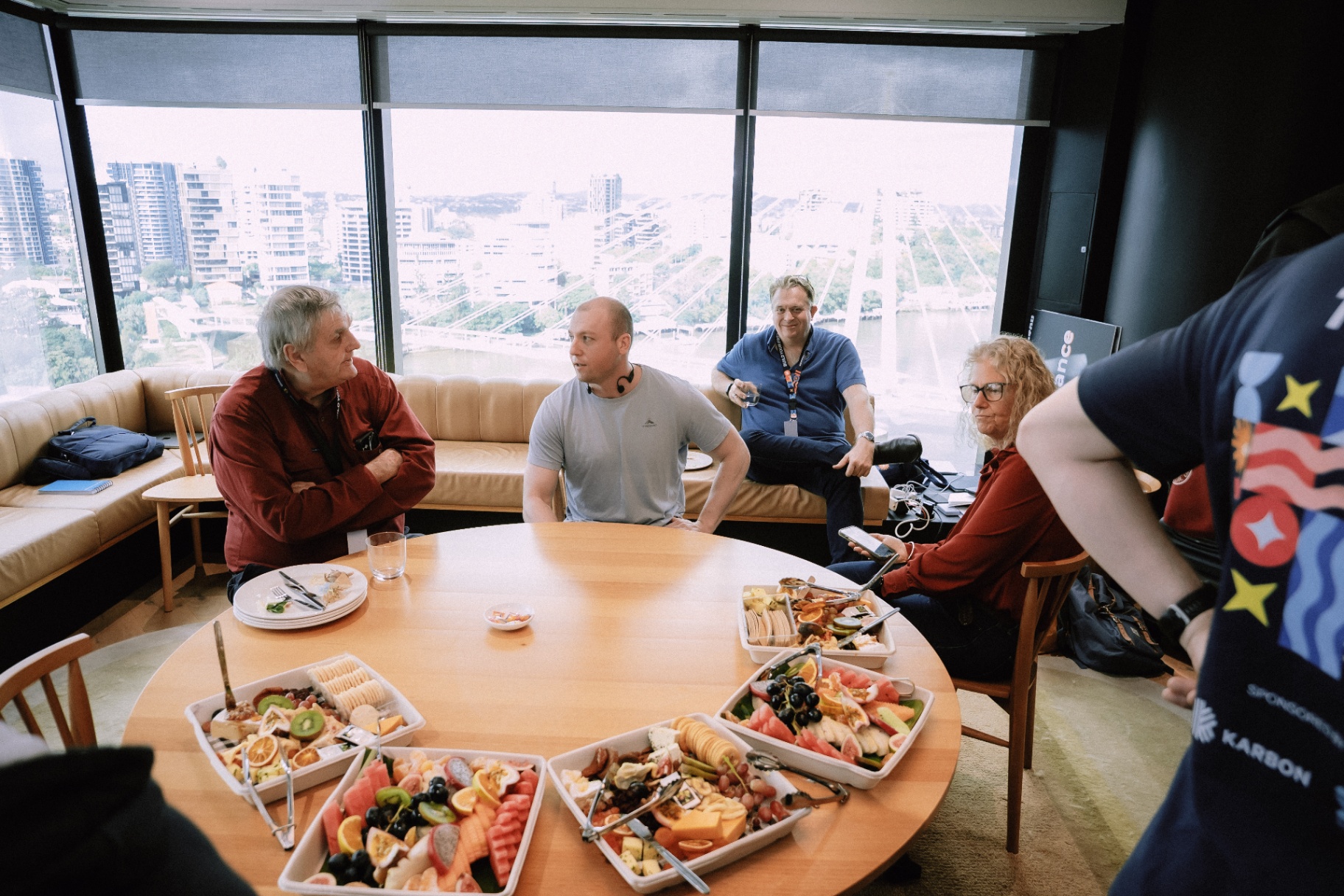 Attendees chatting around a grazing table with Brisbane river views in the background
