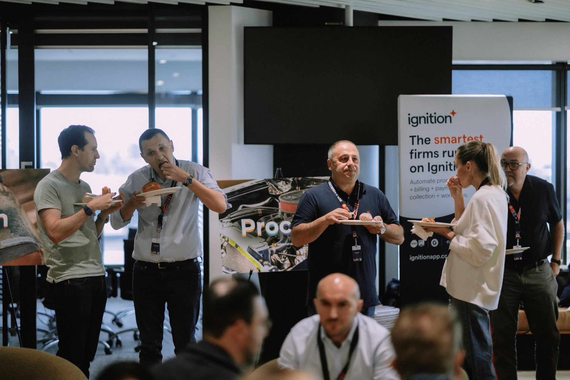 Guests enjoying refreshments beside Ignition sponsor signage during Day 1