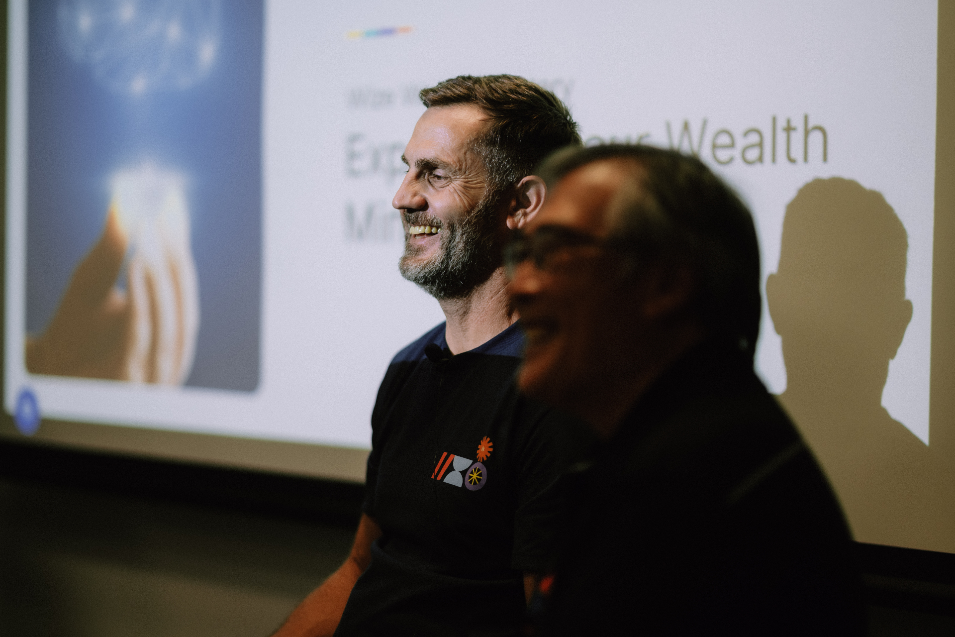 Presenters smiling in front of the screen during the Day 1 session
